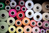 Close-up of colorful polyester spun thread spools lined up in a factory.