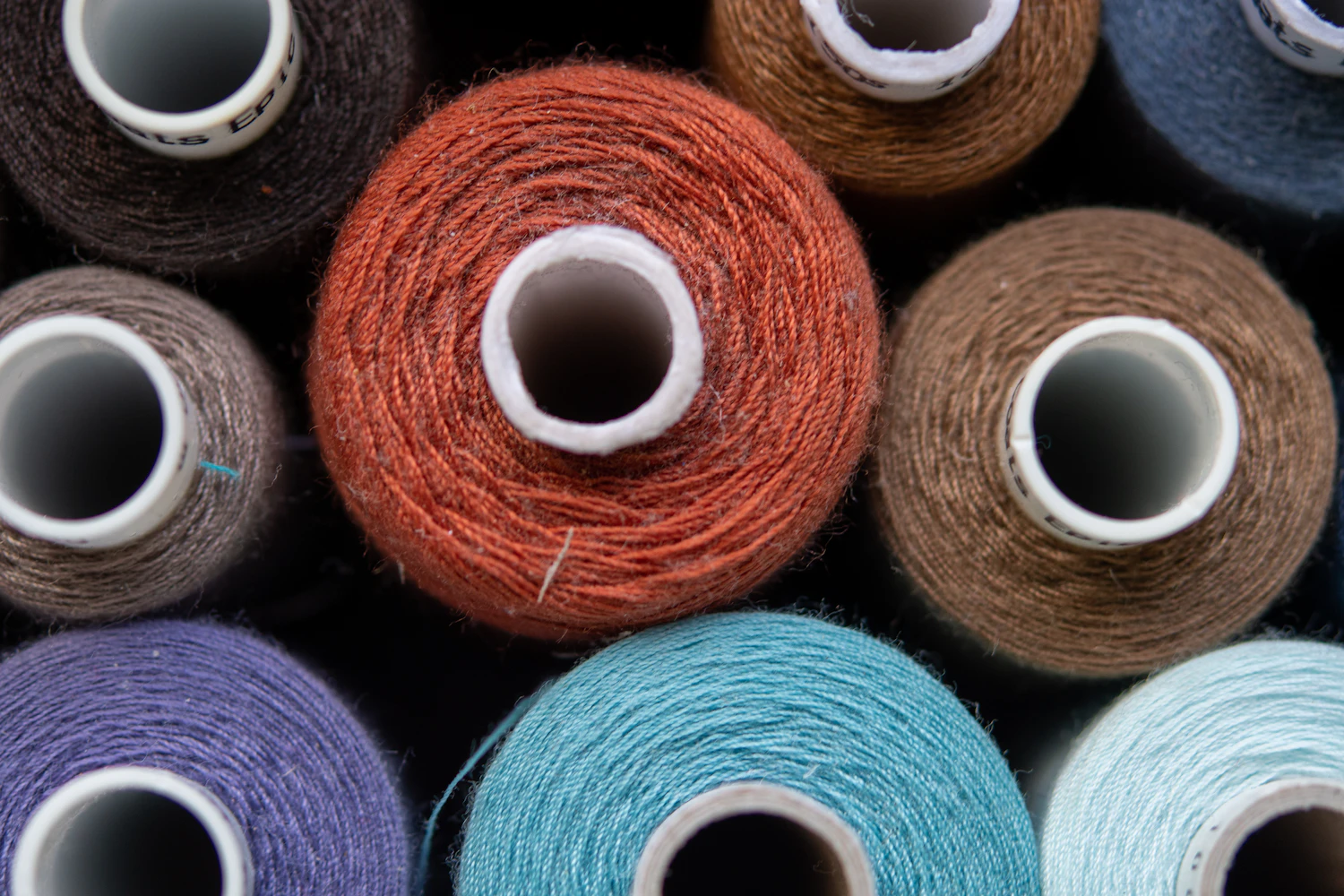Spools of waxed cotton line in rust, blue and brown packed side by side