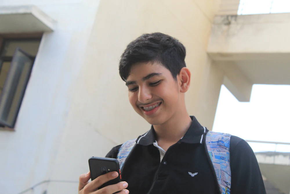 A student smiling at his phone.