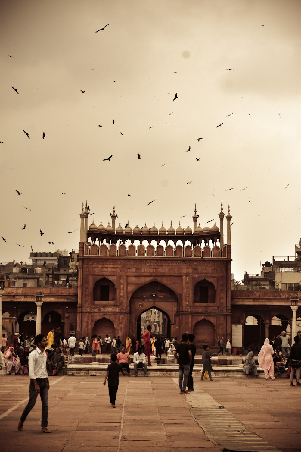 eine große Gruppe von Menschen vor Jama Masjid, Delhi mit vielen fliegenden Vögeln