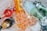 Several bottles, including champagne and sparkling water, are chilled in a bin filled with ice cubes. The bottles are of various colors and shapes, partially submerged in melting ice, creating a refreshing and festive scene.
