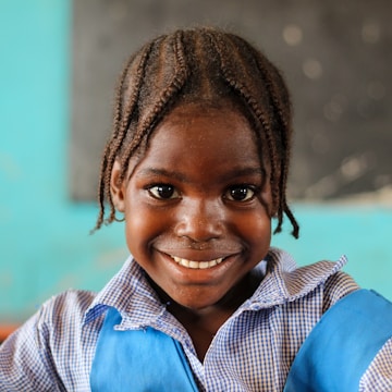 A child smiling warmly while receiving a new school bag under soft natural light