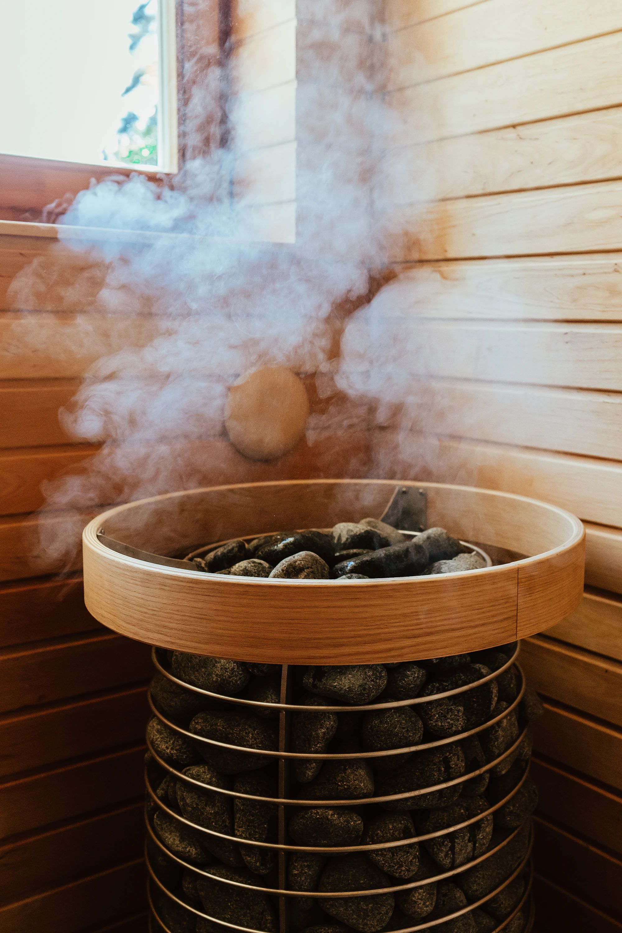 Cabine de sauna en bois clair ouverte sur un paysage de montagne enneigé