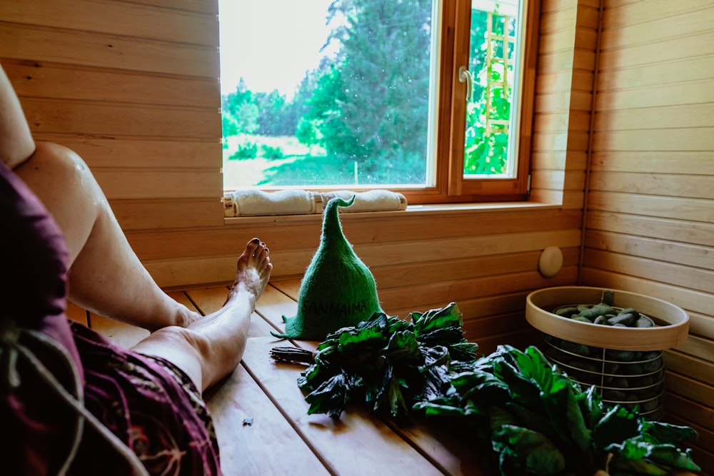 a person lying on a bed next to a window with plants