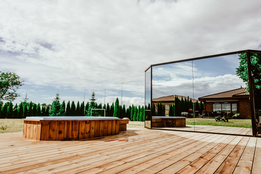 a wooden deck with a metal frame and a building and trees in the background