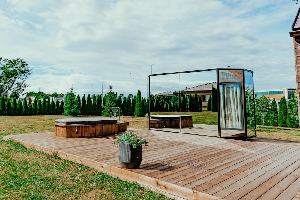 a deck with a gazebo and a wood deck with trees and a building in the background