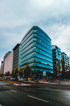 Sleek glass office building in a busy urban center with people entering.