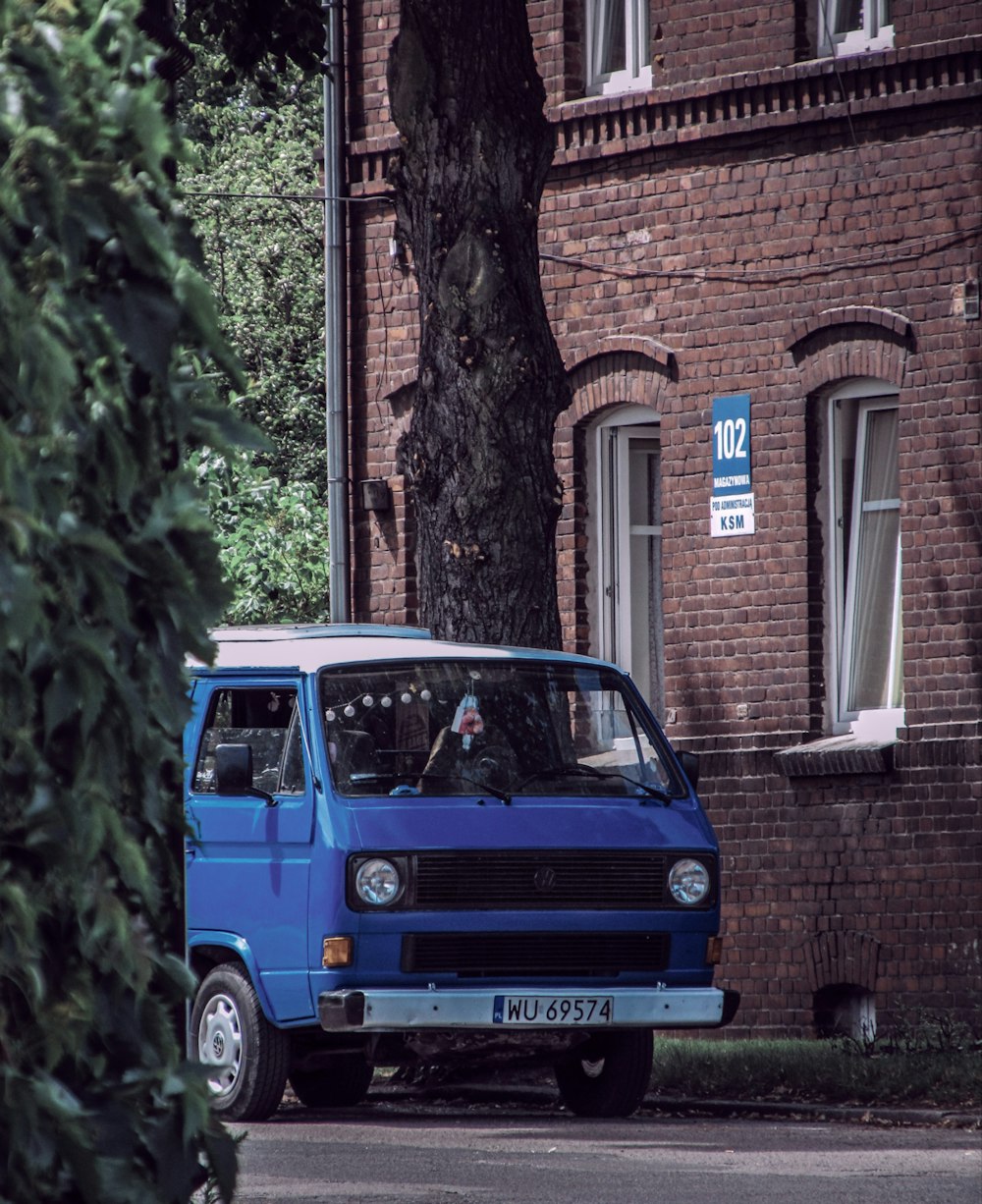 Una camioneta azul estacionada frente a un edificio de ladrillo