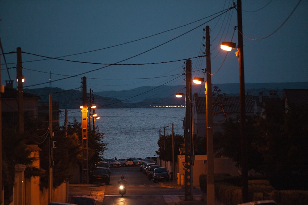 a street with cars and buildings by a body of water