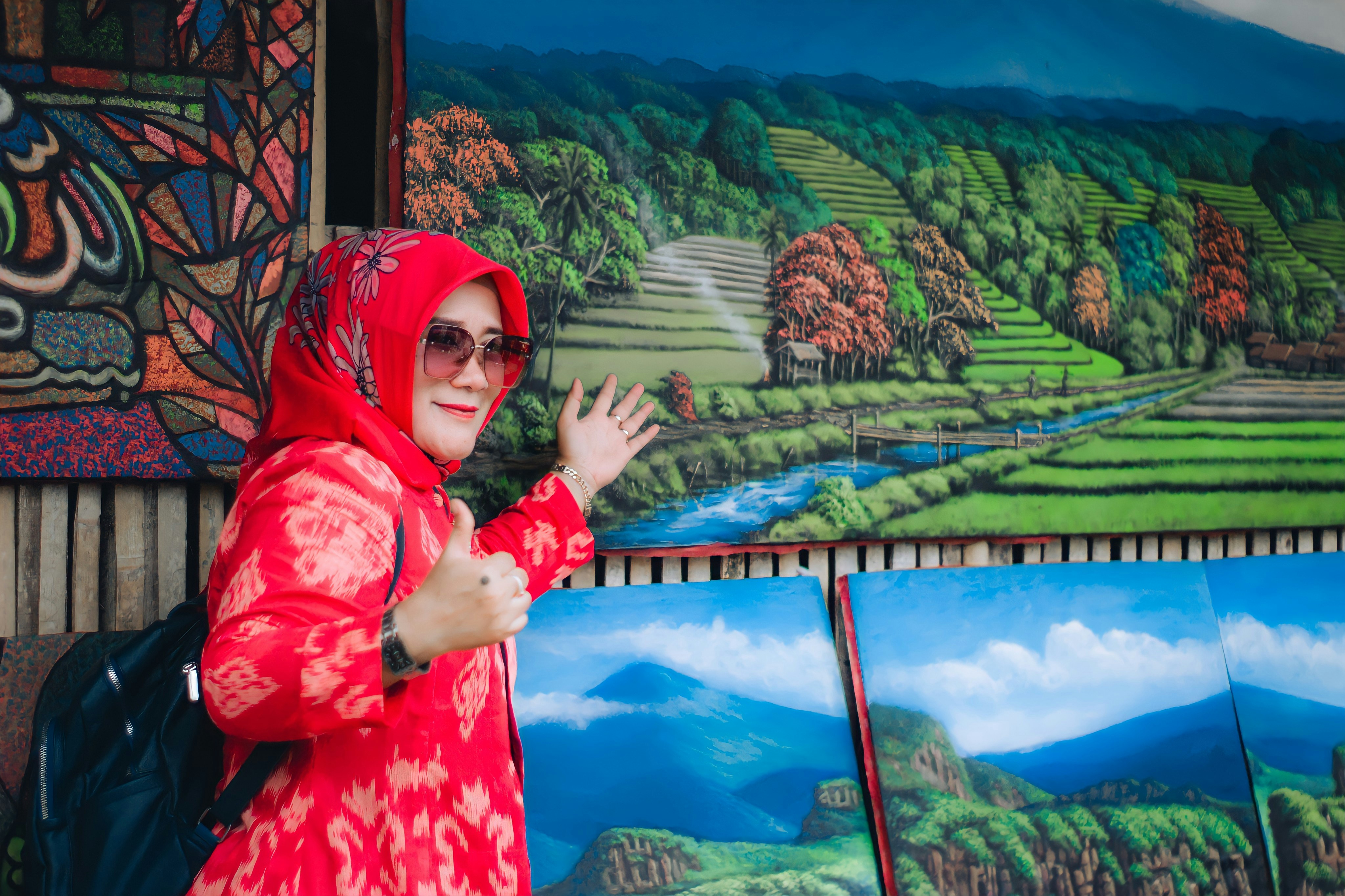 a person wearing a red scarf and glasses standing in front of a painting