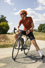 Cyclist wearing sleek, breathable cycling jersey in vibrant colors, outdoors on a sunny day.