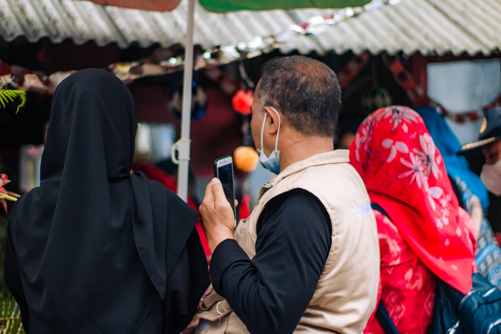 Un hombre tomando una foto de una mujer con un pañuelo rojo en la cabeza