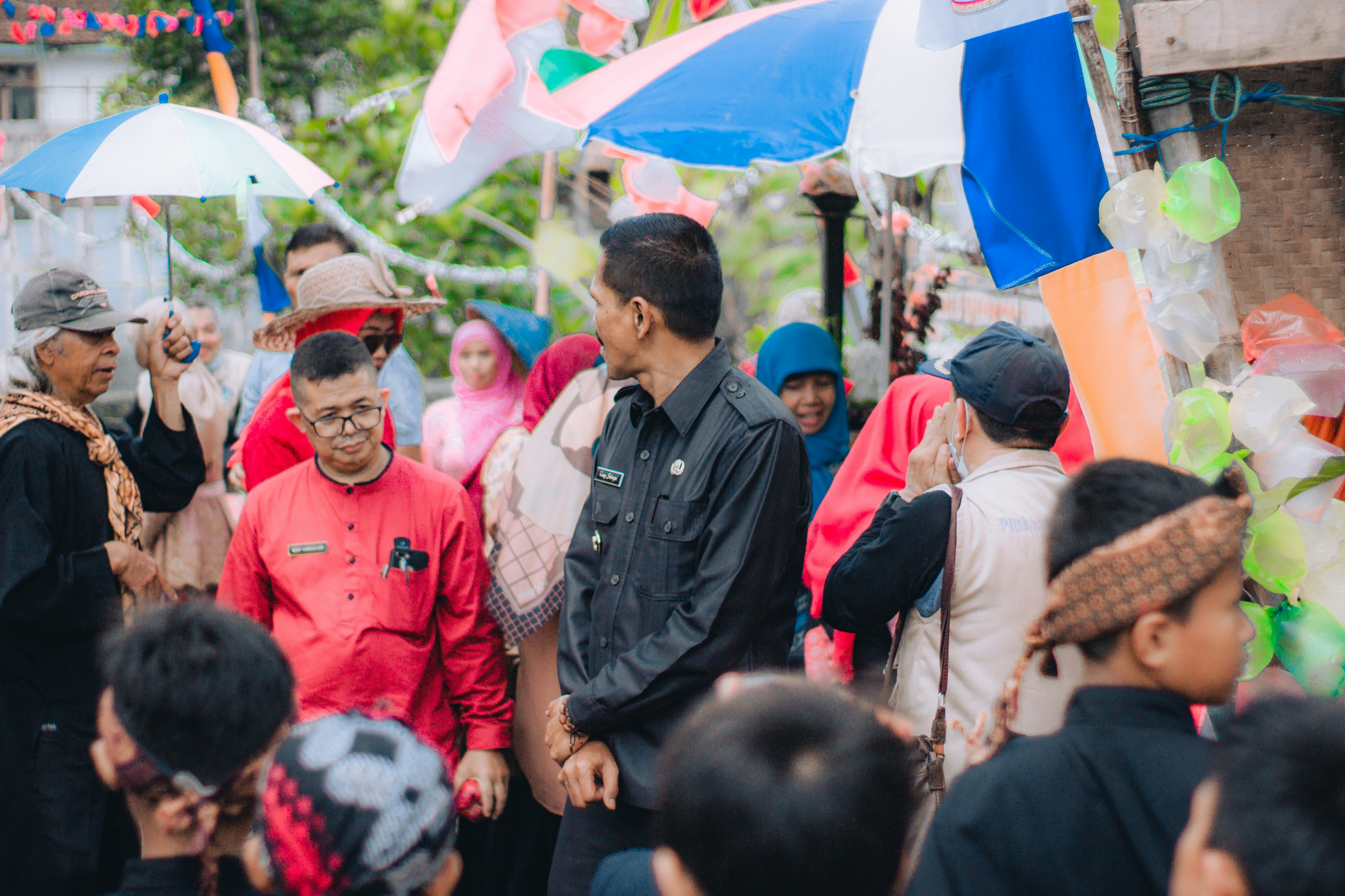 A group of women in traditional Bengali attire, protesting vehemently with placards, some holding sticks, reflecting anger and demands for justice in a rural setting.