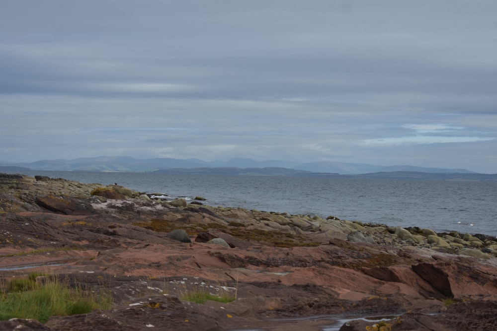 a rocky beach with a body of water in the background