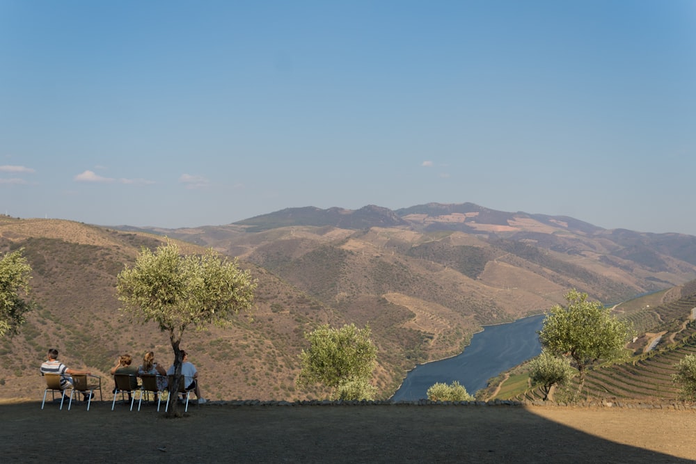 Eine Gruppe von Menschen sitzt auf einer Bank mit Blick auf ein Tal