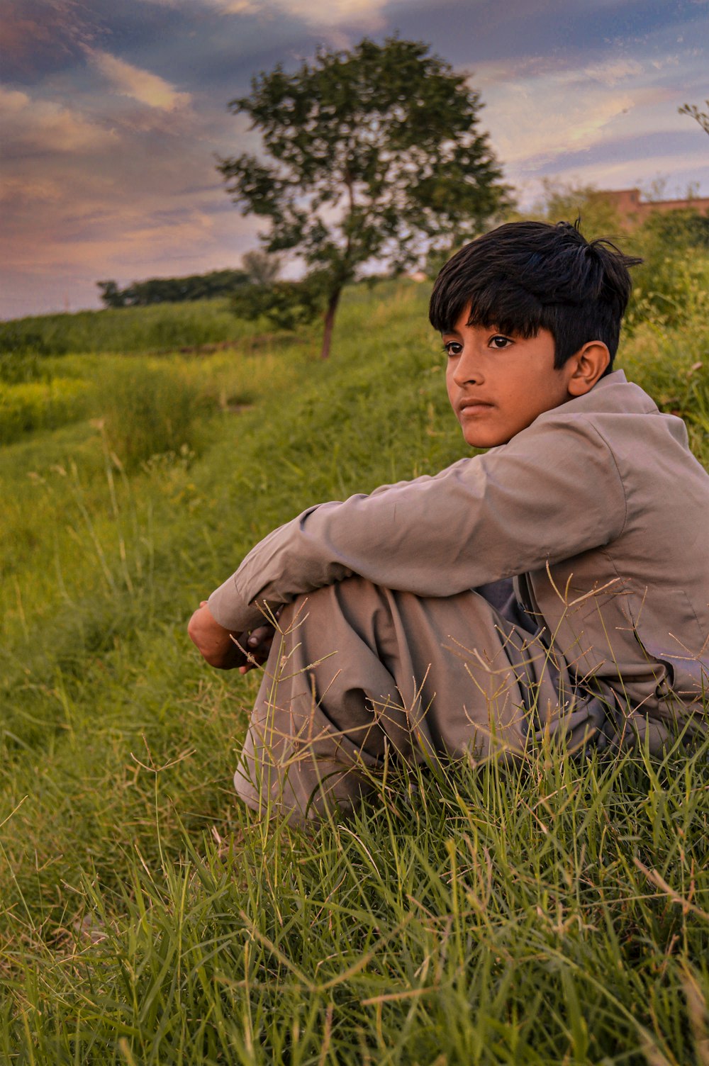 a boy sitting in a grassy field