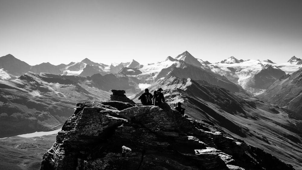 a group of people sitting on a rock in the middle of a mountain range