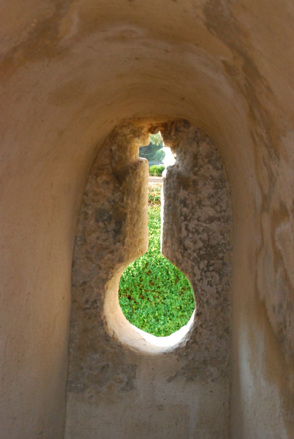 a view of a grass field through a hole in a stone wall