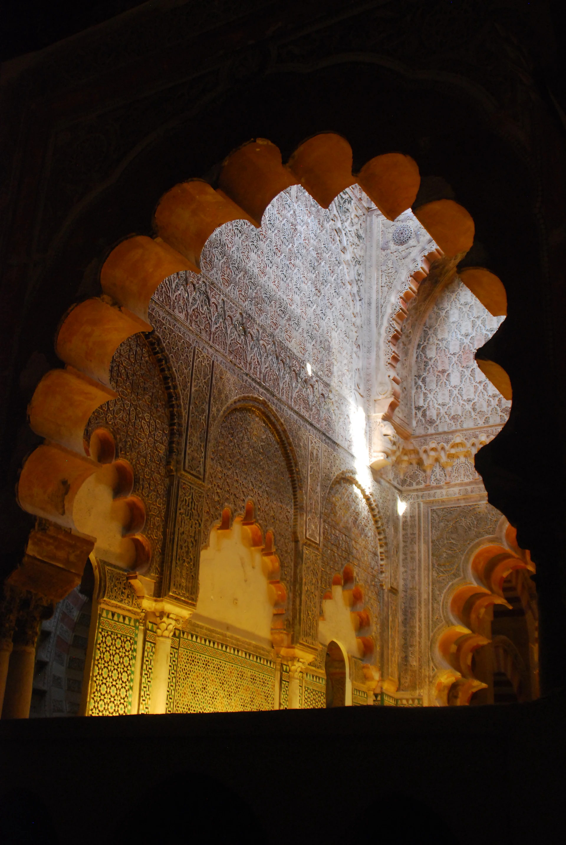 A close-up of a handcrafted wooden arch detail, showing natural wood grain and delicate floral accents under warm golden light.
