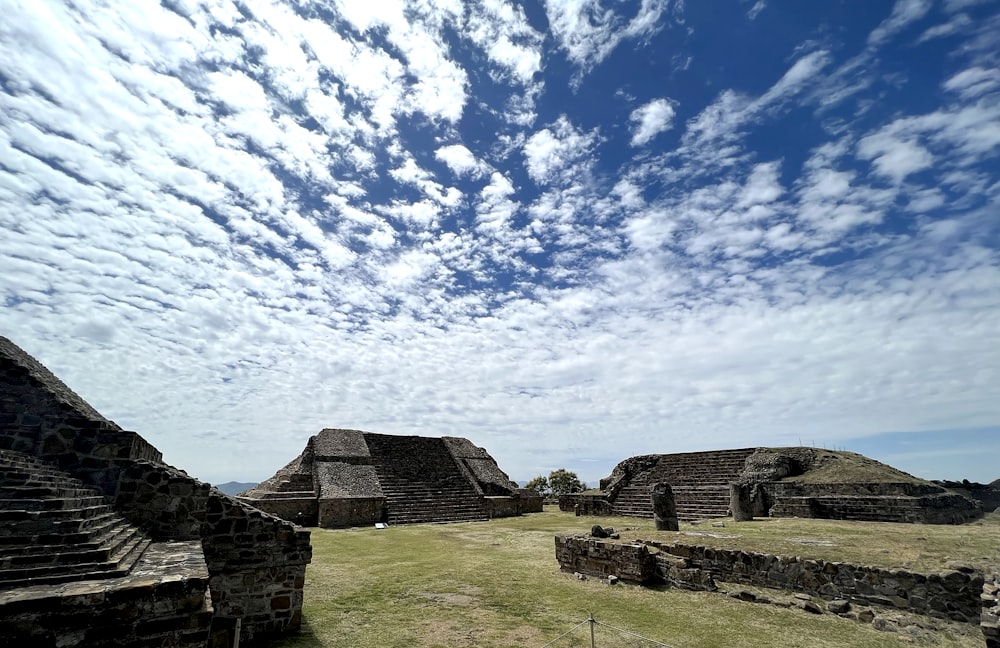 a stone wall and grass with a blue sky and clouds