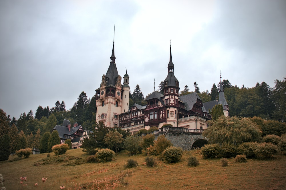 un castillo con muchas agujas con el castillo de Peleș al fondo