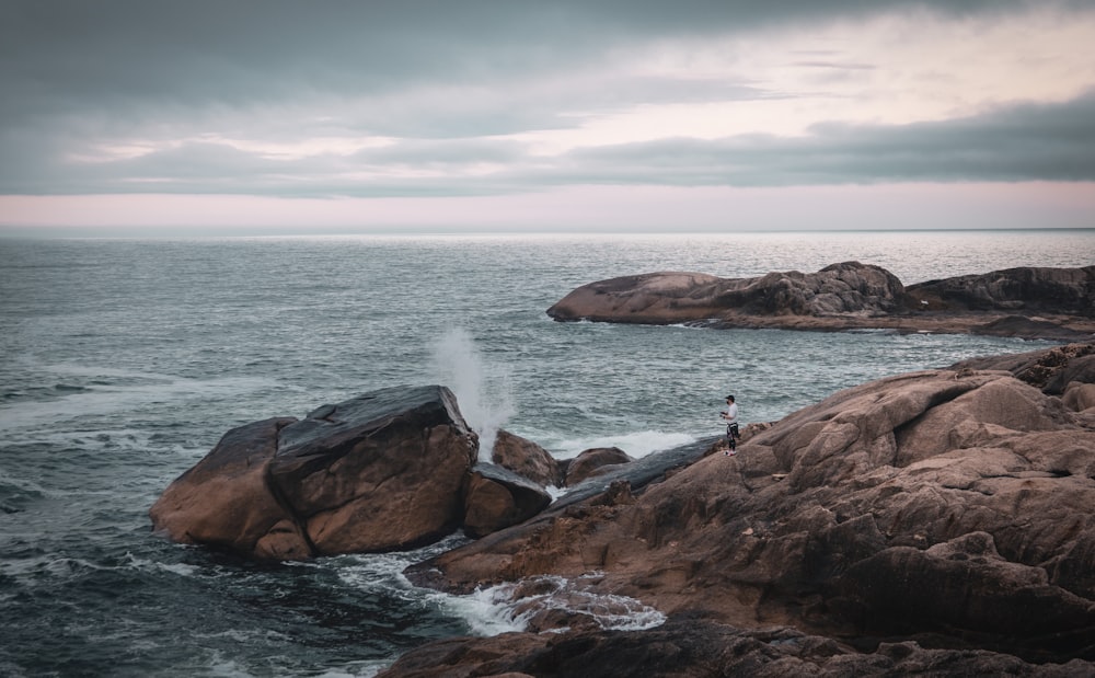 a couple people standing on rocks in the water