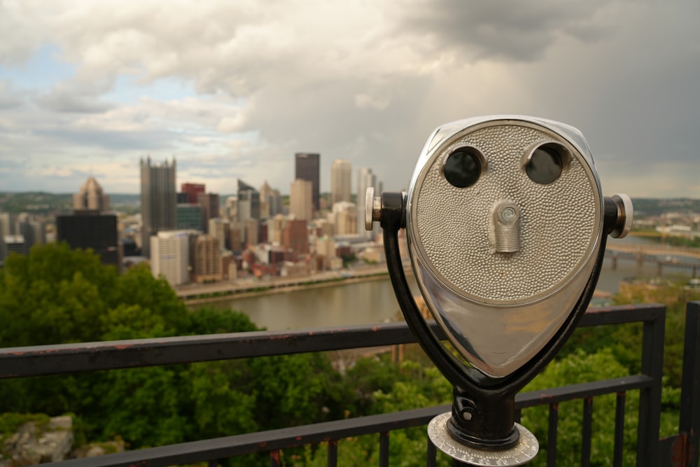 a metal object on a railing overlooking a city