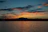 Close-up of a coaster featuring a vivid orange and purple sunset over a calm lake.