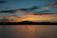 Close-up of a coaster featuring a vivid orange and purple sunset over a calm lake.