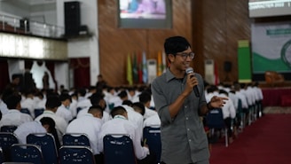 a person speaking into a microphone in front of a group of people