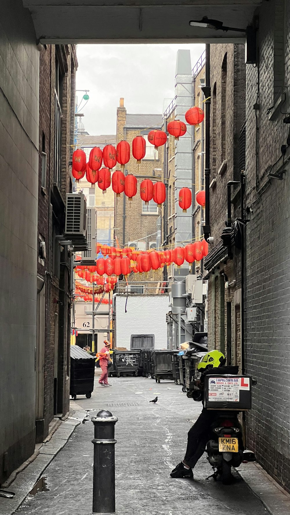 a person walking down a sidewalk with red lanterns from the ceiling