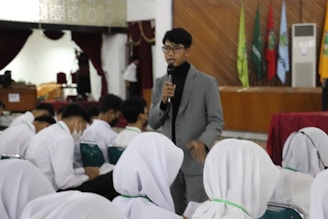 a person speaking into a microphone in front of a group of people