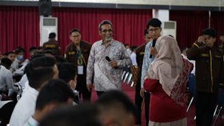 a group of people standing in a room with a person holding a microphone