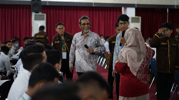 a group of people standing in a room with a person holding a microphone