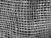 A close-up view of a woven mesh material creates a grid-like pattern. The texture is intricate, with intersecting lines forming a series of squares. The material appears translucent and shiny, giving it a reflective quality.