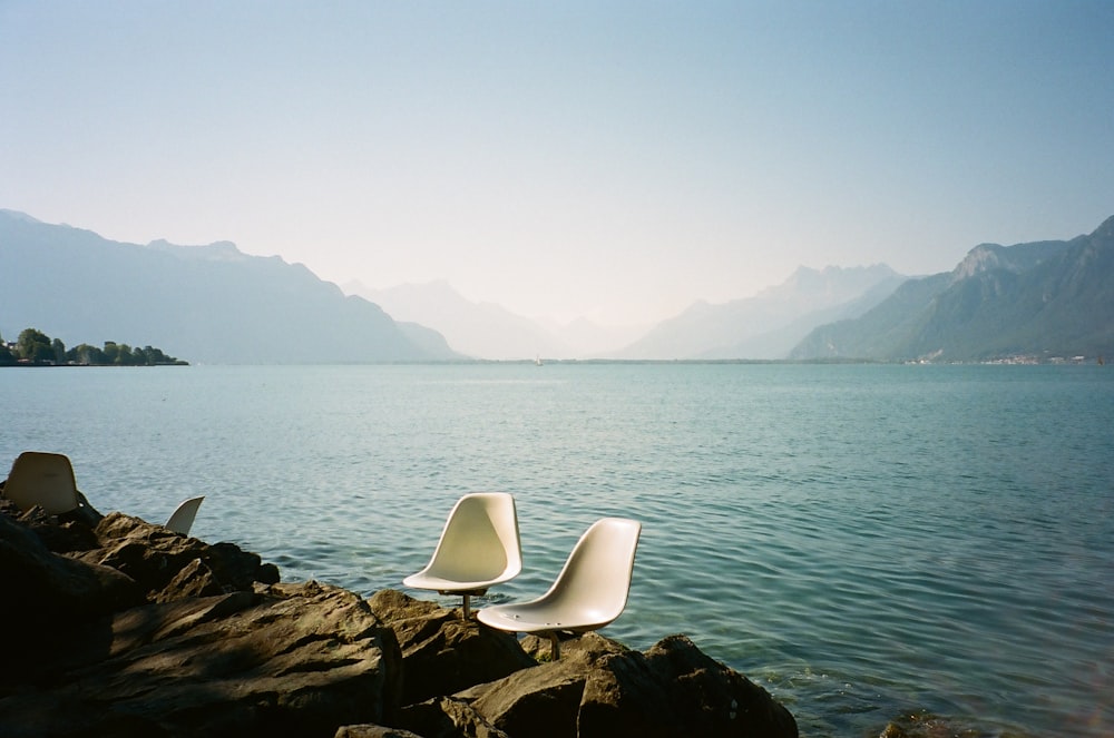 a chair on a rocky shore by a body of water