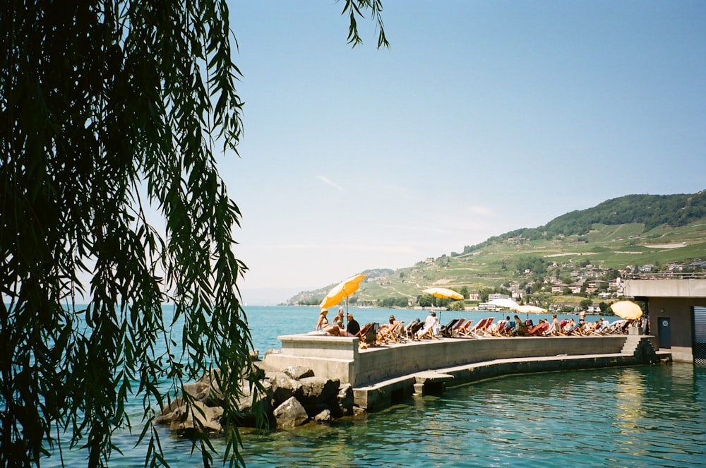 a group of people sitting on a dock over a body of water