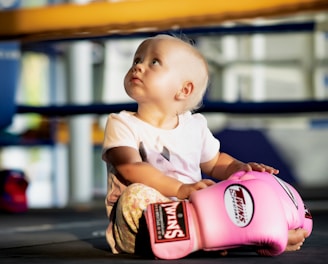 a baby sitting in a pink baseball glove