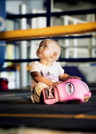 a baby sitting in a pink baseball glove