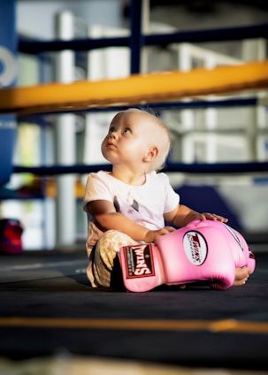 a baby sitting in a pink baseball glove