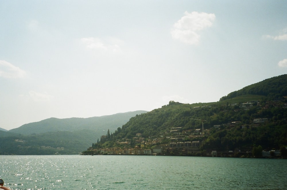 a body of water with buildings and hills in the background