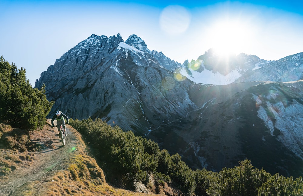 a person riding a bike on a trail in front of a mountain
