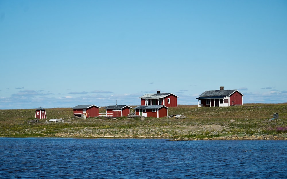 a group of red buildings on a hill by a body of water