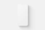 A minimalist design featuring a white smartphone with a blank screen, positioned centrally against a white background. The image emphasizes simplicity and clean lines.
