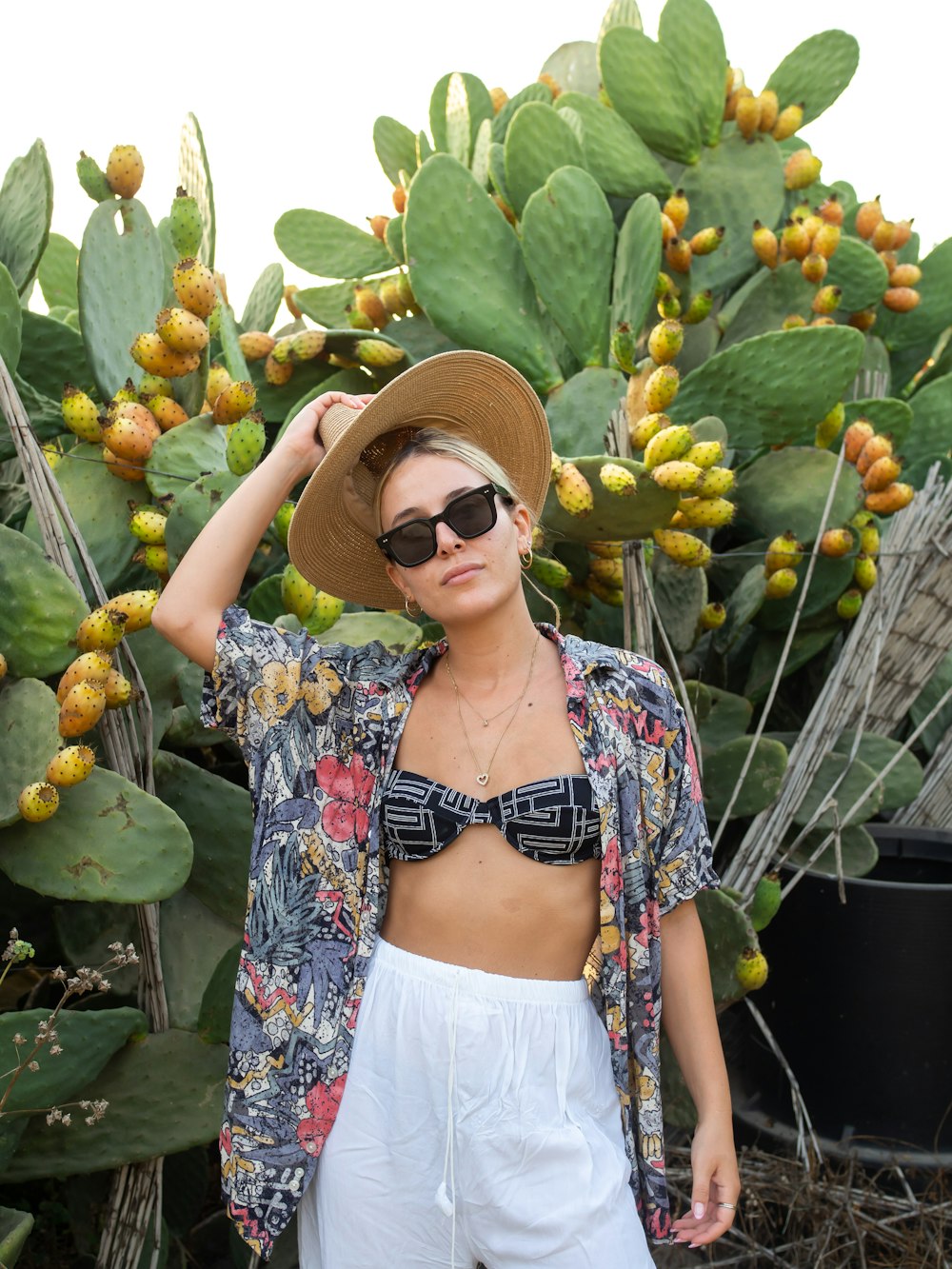 Eine Person mit Hut und Sonnenbrille steht vor einem Strauß Obst