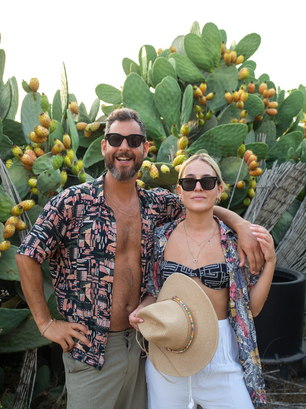 a man and woman posing for a picture in front of a large cactus