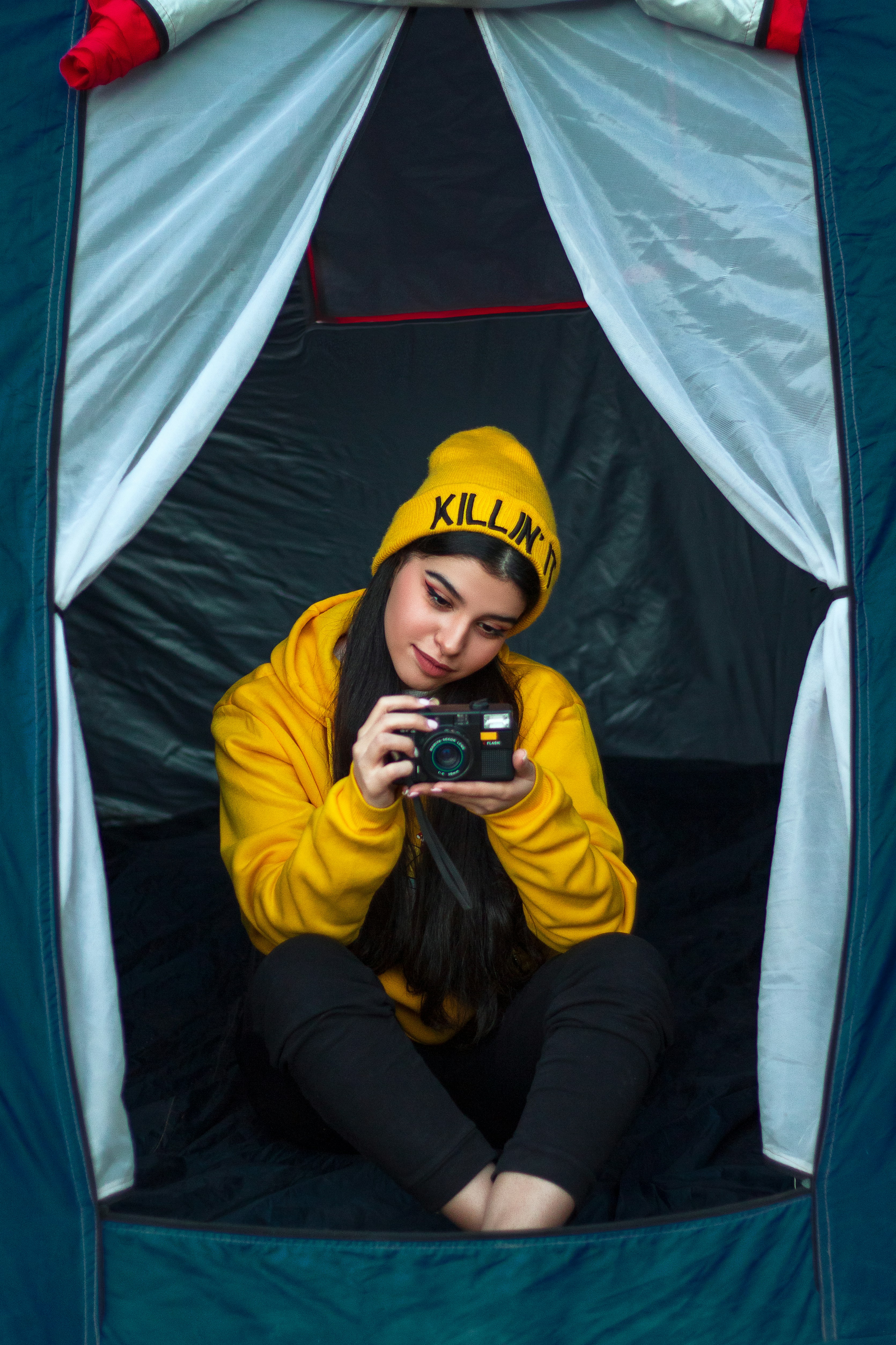 a girl in a yellow shirt taking a selfie in a tent