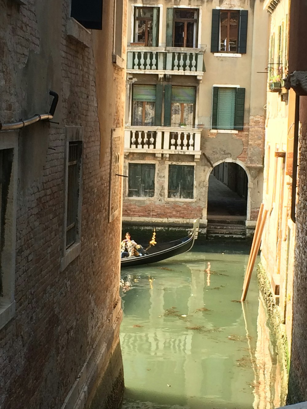 a couple people in a boat in a canal between buildings