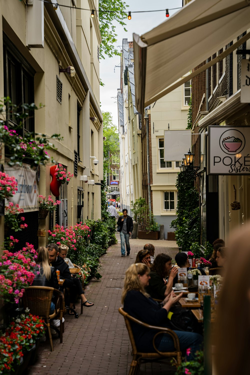 people sitting at tables in a narrow alley between buildings