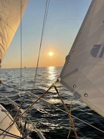 A serene sunset view from the catamaran with calm seas and warm golden light.